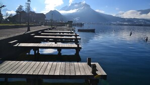A wooden pier extending into calm water with a mountain in the background.