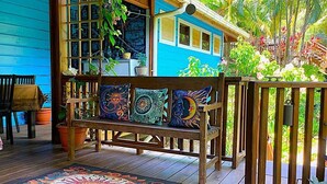 Une terrasse en bois avec un banc, des coussins colorés et un tapis à motifs.