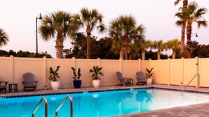 A swimming pool with lounge chairs and potted plants, surrounded by a white fence and palm trees. - Beach Condo & Pool Relaxing Getaway! Short Stride to Sandy Beach's. Unit 8 (Panama City Beach)