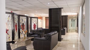 Un hall d’entrée moderne comprenant un comptoir d’accueil, un espace salon et des œuvres d’art accrochées aux murs.