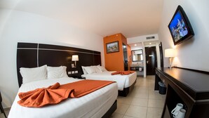 Une chambre d’hôtel avec deux lits, une télévision, un bureau et une salle de bain que l’on aperçoit à l’arrière-plan.