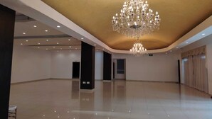 Un vaste hall agrémenté d’un grand lustre, d’un éclairage encastré et d’un plancher poli.