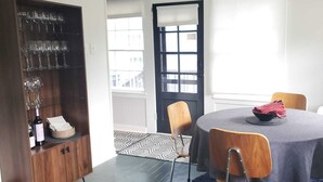 Un comedor con una mesa redonda, cuatro sillas, un botellero y una puerta con ventanal.