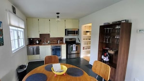Una cocina compacta con electrodomésticos modernos, un comedor con una mesa redonda y una alacena para vinos.