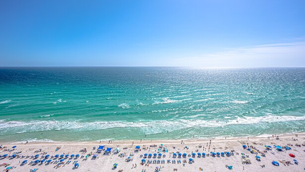 Ein Strand mit vielen Sonnenschirmen und Menschen.