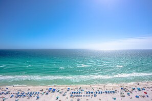 A beach with numerous umbrellas and people.