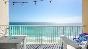 Ein Balkon mit Blick auf den Ozean, ein Tisch und zwei Stühle.