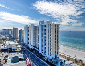 A high-rise hotel with multiple floors, a beach view, and a pool area.