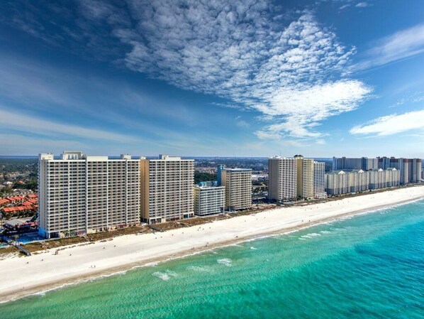 A coastal hotel with multiple high-rise buildings, a beachfront, and clear skies.