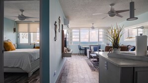 A modern bedroom with a bed, a ceiling fan, and a view of the ocean. - Oceanfront Condo • Pool • Near Seven Seas Beach (Fajardo)