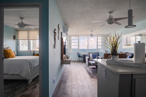 Une chambre à coucher moderne avec un lit, un ventilateur de plafond et une vue sur l’océan.