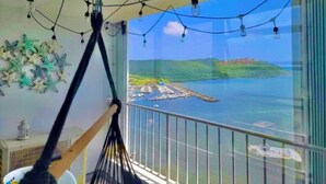 A hammock on a balcony with a view of a body of water and a distant island. - Oceanfront Condo • Pool • Near Seven Seas Beach (Fajardo)