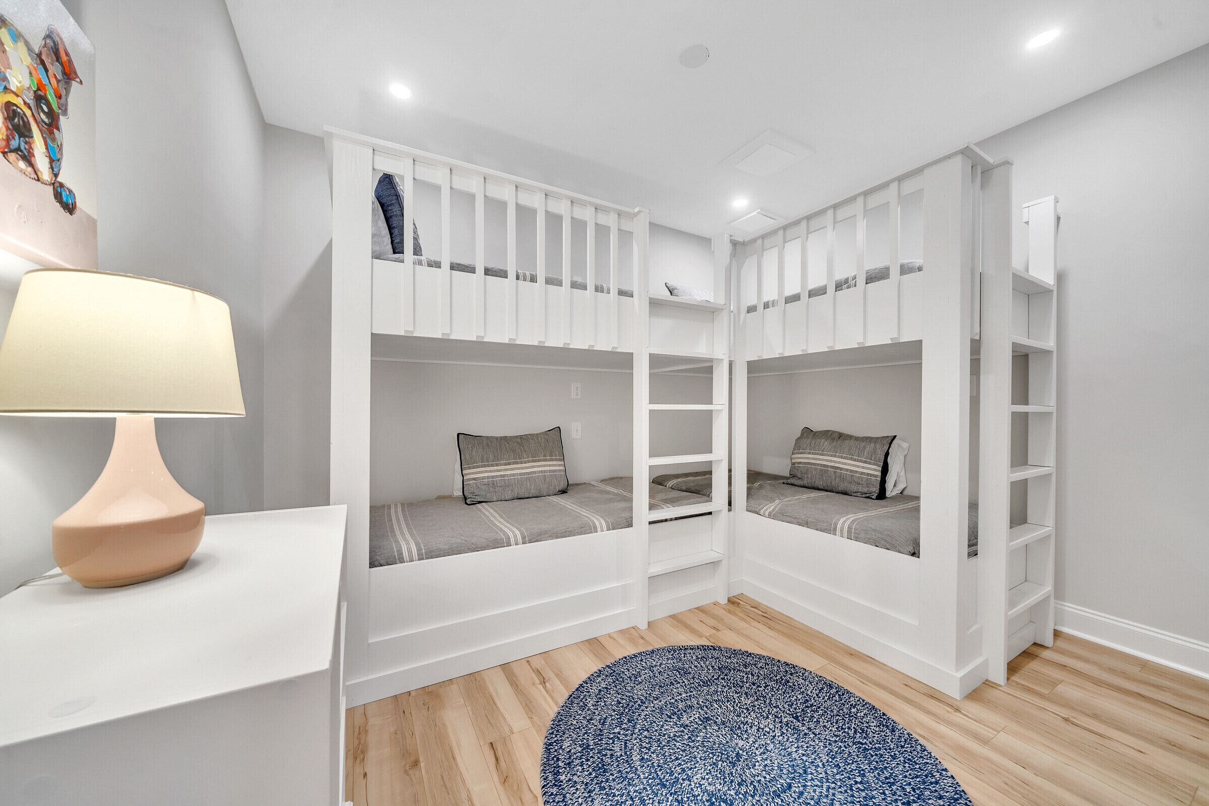 Une chambre avec des lits superposés, une lampe et un tapis bleu.