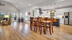 Een ruime keuken met houten vloeren, witte kasten en moderne apparatuur.