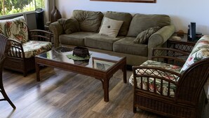Un salon comprenant un canapé, deux fauteuils, une table basse et un tableau accroché au mur.
