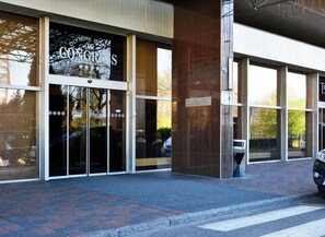 A building entrance with glass doors, a sign for 'Olympiapik Congress', and a brick-paved area. - Olympik Congress Hotel (Prague)