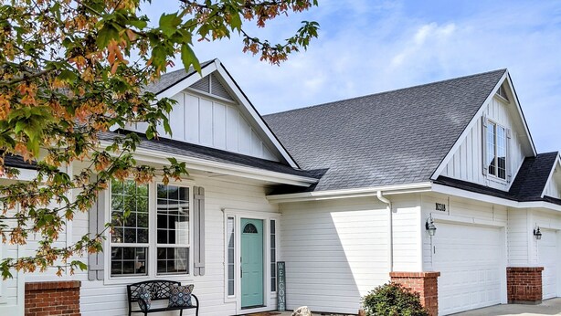 A single-story house with a front porch, a green door, and a mailbox.