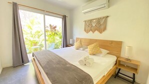 Camera da letto con un letto grande, una ventola a soffitto, un condizionatore d'aria e vista sul verde.