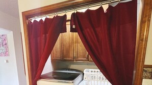 Une petite buanderie équipée d’un lave-linge et d’un sèche-linge, de meubles en bois et d’un sol carrelé.