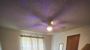 Une chambre à coucher comprenant un lit, une commode en bois, une chaise, une petite table, un globe terrestre et un miroir.