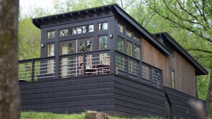A modern wooden cabin with a balcony, large windows, and a rustic design. - Wildwood Resort & Marina (Granville)