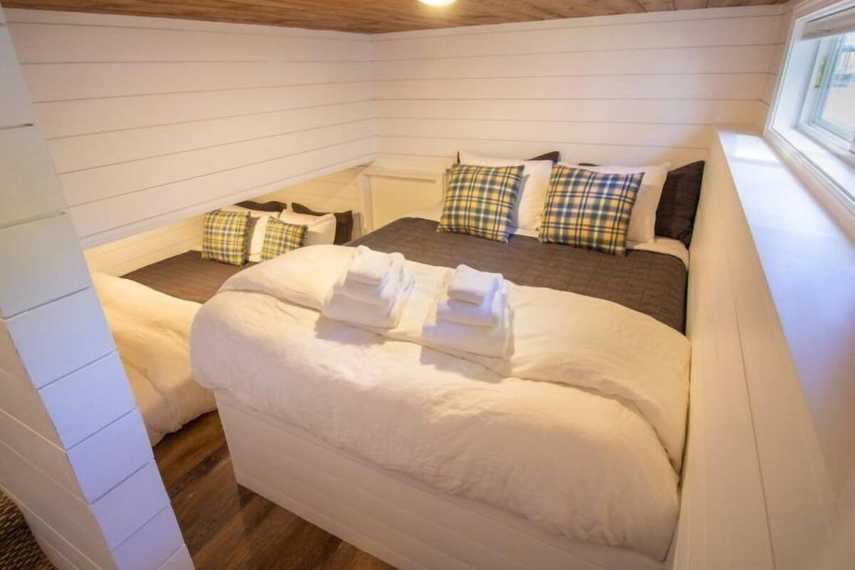 A cozy bedroom with a large bed, plaid pillows, and neatly folded towels.