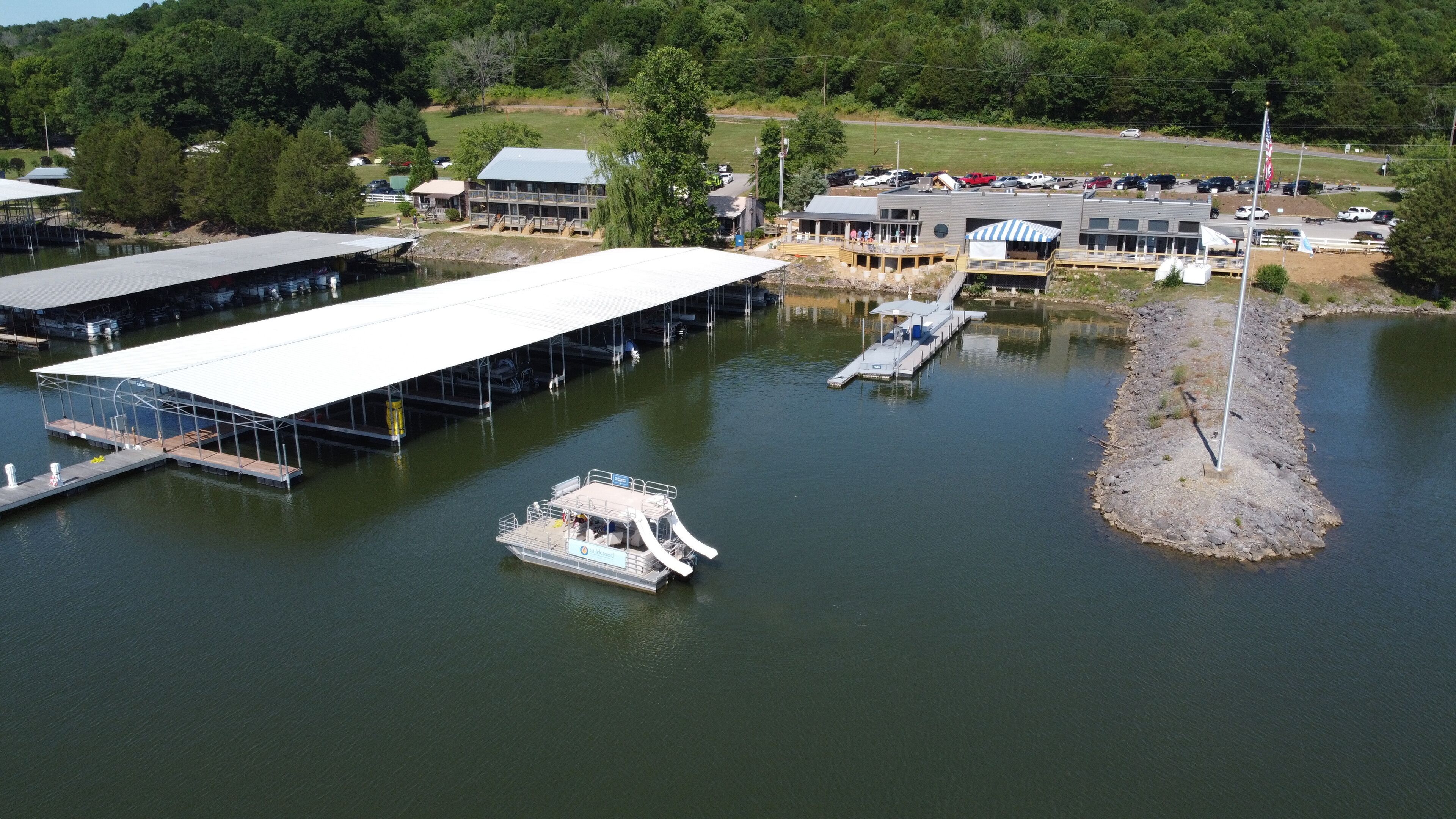 A marina with docked boats, a covered boat launch ramp, and a building with a large overhanging roof.