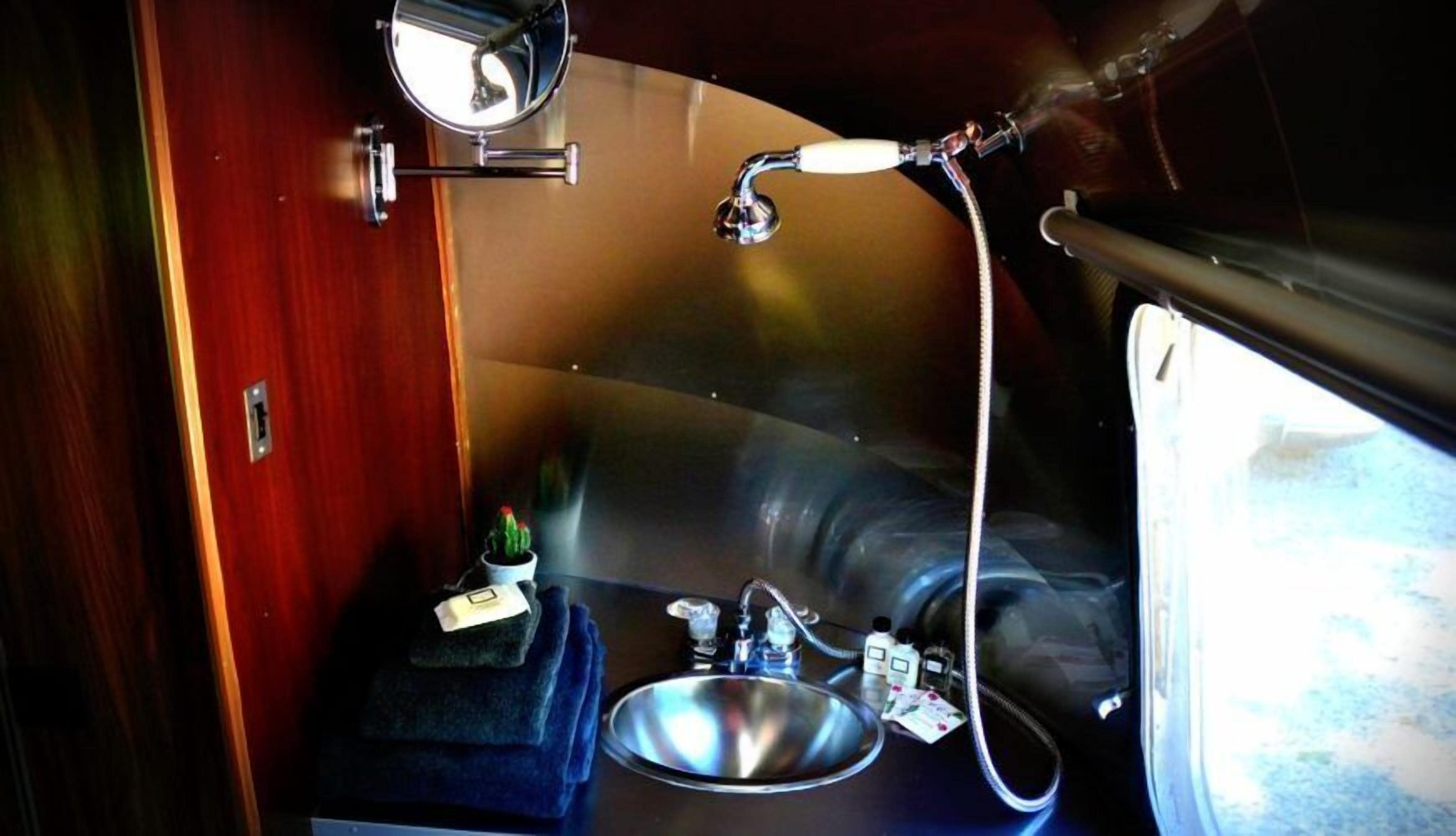 A compact bathroom with a sink, mirror, and shower.
