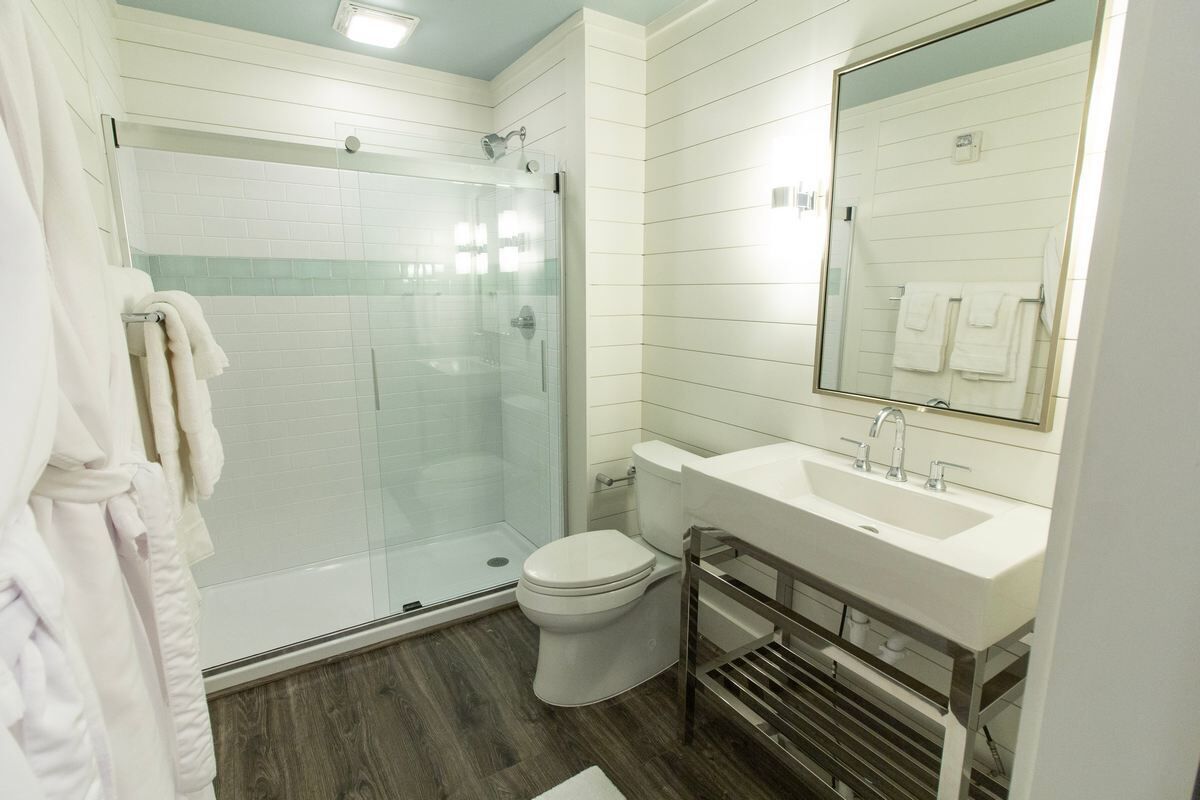 A modern bathroom with a glass-enclosed shower, a white sink, and a toilet.