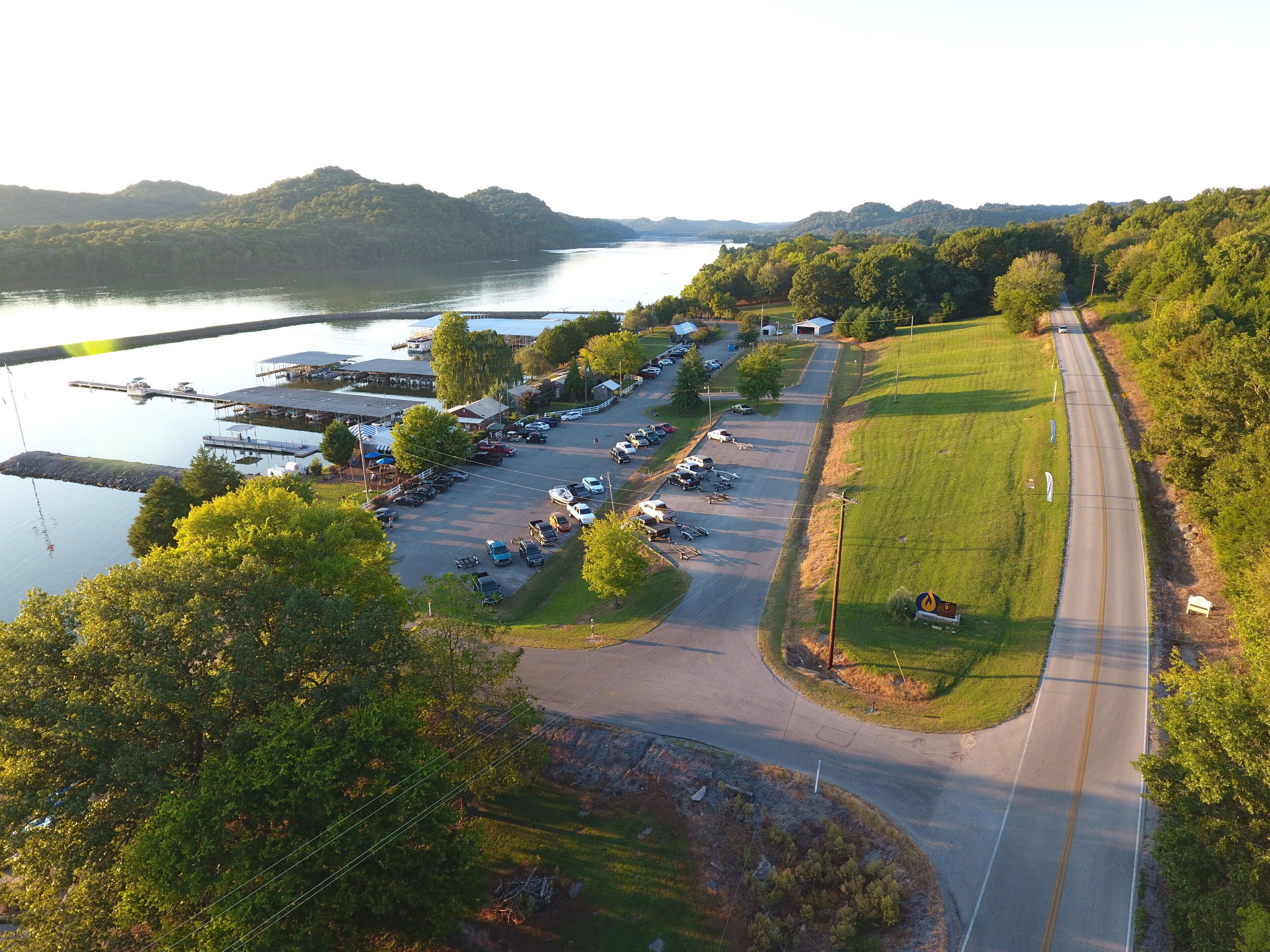 An aerial view of a parking lot adjacent to a body of water with a road curving around it.