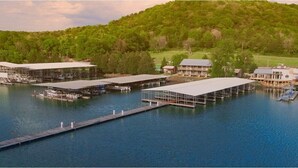 A marina with multiple docked boats, covered boat houses, and a long pier extending into the water. - Wildwood Resort & Marina (Granville)