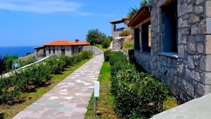 A stone building with a tiled pathway leading to a red-roofed structure. - Villa Molyvos Castle (Lesvos)