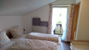 Una habitación con dos camas, un radiador y vistas al exterior por una puerta.