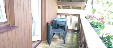 Un balcón con suelo de baldosas, una silla y una mesita.