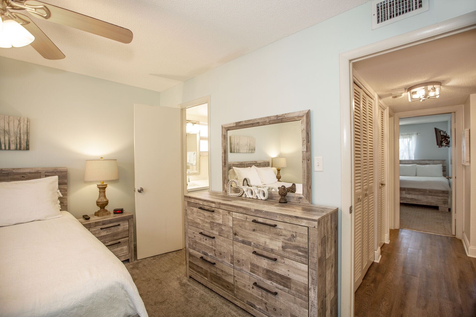 A bedroom with a bed, dresser, and a ceiling fan.