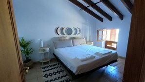 A bedroom with a bed, a nightstand, a potted plant, a mirror, and a window with blinds. - VILLA MARIA, NEAR PALMA BEACH (Sant Jordi, Palma)