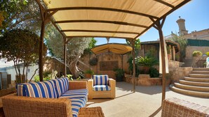 A covered outdoor seating area with wicker furniture and striped cushions, surrounded by plants and a stone staircase. - VILLA MARIA, NEAR PALMA BEACH (Sant Jordi, Palma)