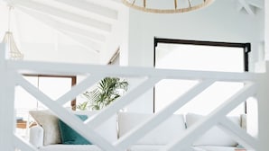 Un interno moderno con una parete divisoria bianca a motivi geometrici, un divano bianco e un lampadario sospeso.