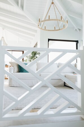 A modern interior with a white geometric-patterned partition, a white sofa set, and a hanging chandelier.