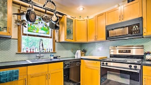 A kitchen with wooden cabinets, a dishwasher, a microwave, a stove, and a tiled backsplash. - Charming Hampton Bays Home 5 Mi to Cooper’s Beach (Hampton Bays)