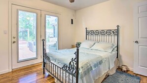 A bedroom with a bed, a ceiling fan, a window, and a door. - Charming Hampton Bays Home 5 Mi to Cooper’s Beach (Hampton Bays)