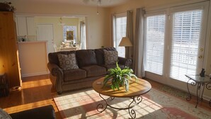 A living room with a brown leather sofa, a round wooden coffee table with a plant, and a patterned rug.