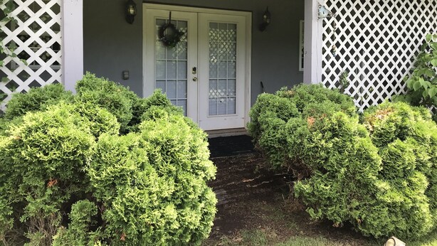 A porch with a white door, a wreath, and a lattice wall.