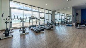 Una palestra con tapis roulant, ellittiche e attrezzature per pesi, ampie finestre e pavimento in legno.