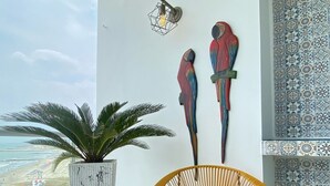 Un balcone con una sedia in vimini, una pianta in vaso e due sculture di uccelli a parete.