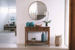A wooden console table with a round mirror, teal vases, and a potted orchid. - Sao Vicente Lodge (Ponta Delgada)