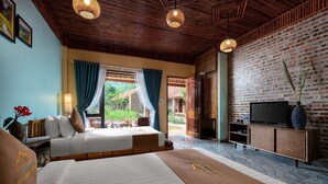 Habitación de hotel con dos camas, televisión y vista al jardín.