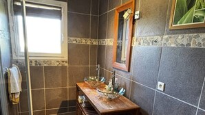 Une salle de bain avec un lavabo en verre, un meuble-lavabo en bois, un miroir et une fenêtre.