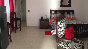 Ein Schlafzimmer mit Bett, Nachttisch, Stuhl, Kleiderschrank und Spiegel an der Wand.