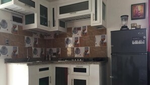 Eine Küche mit weißen Schränken, einem schwarzen Kühlschrank und einer gefliesten Rückwand.